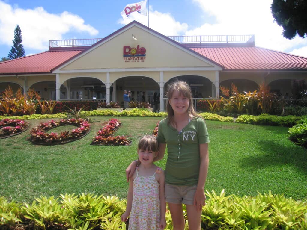 Two young girls posing at entrance to Dole Plantation on Oahu, Hawaii.