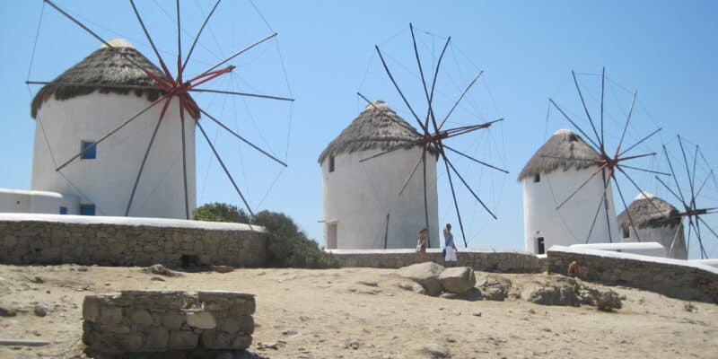 three windmills set against blue sky on mykonos