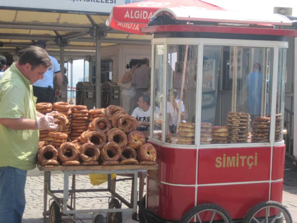 Man with red simit cart and stacks of simit.