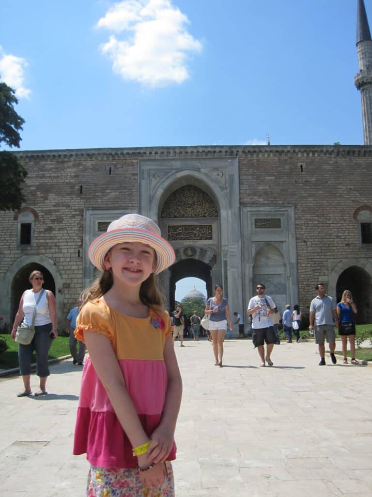 Young girl posing outside gate to Topkapi Palace in Istanbul.