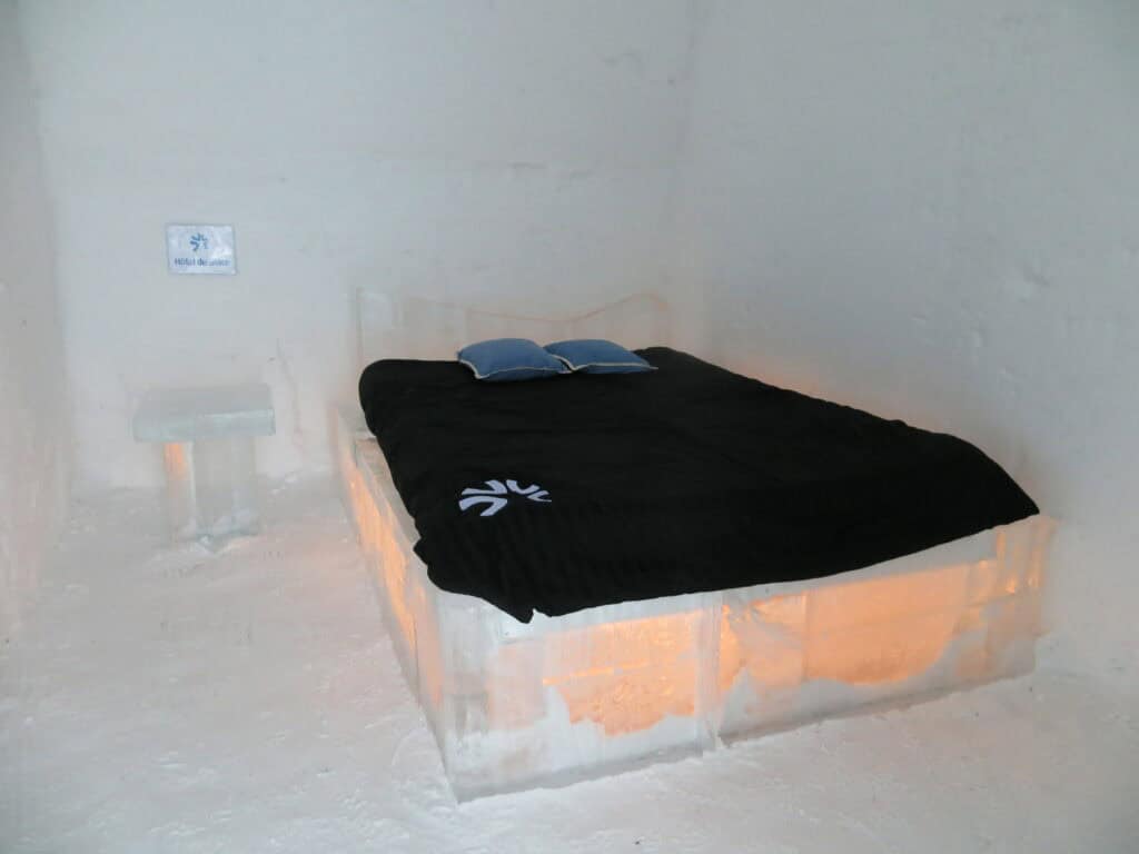 ice hotel - bed of ice with dark blue bed covering and two lighter blue pillows - Quebec Ice Hotel.