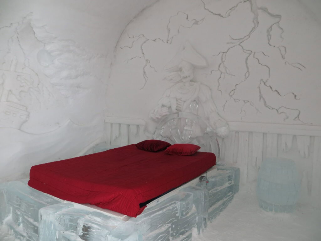 quebec ice hotel ghost ship room with red covering on ice bed.