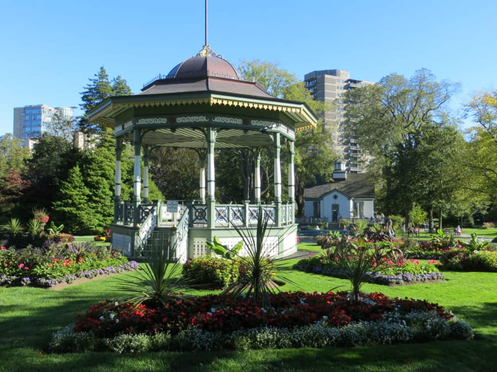 Green and white Bandstand in Halifax Public Gardens surrounded by beds of flowers and bushes.