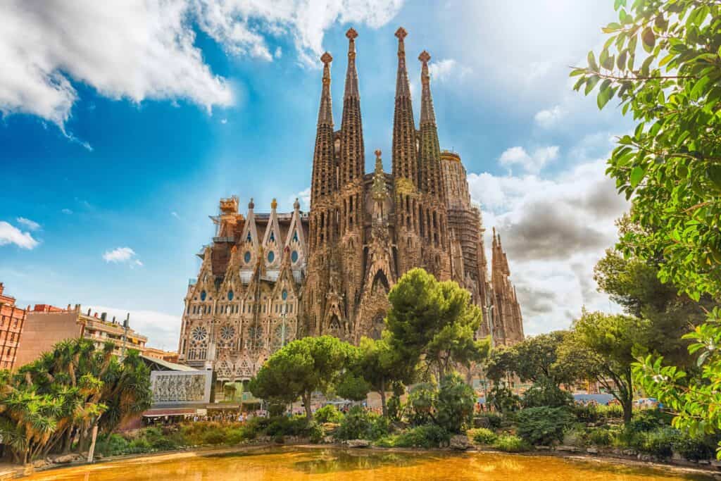 The Sagrada Familia in Barcelona, Spain on a sunny day with bright blue sky and white clouds.