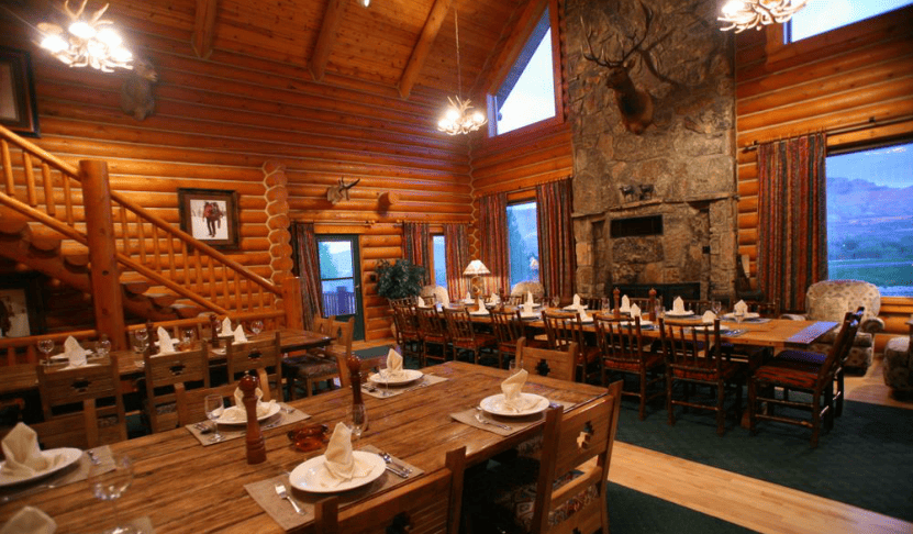 dining tables set up in log buuilding with large stone fireplace.