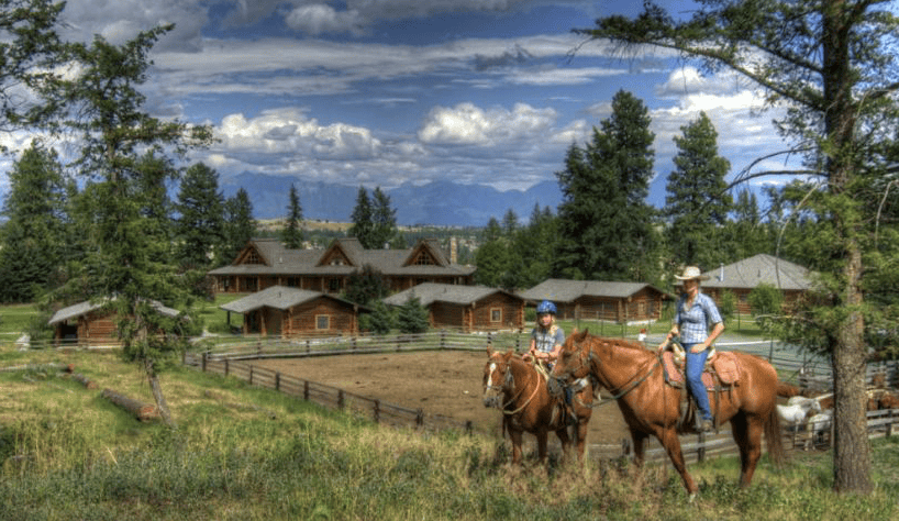 two people on horse with cabins in background