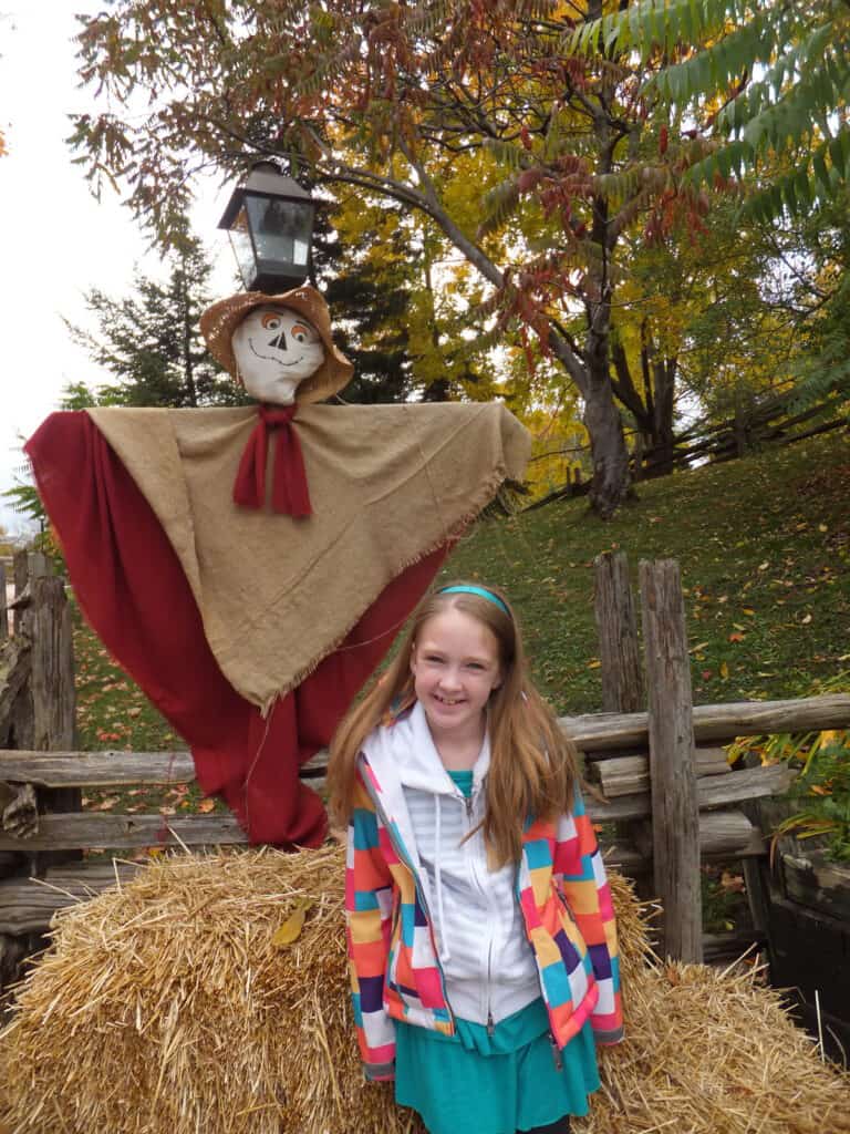 Young girl standing in front of scarecrow at Black Creek Pioneer Village.