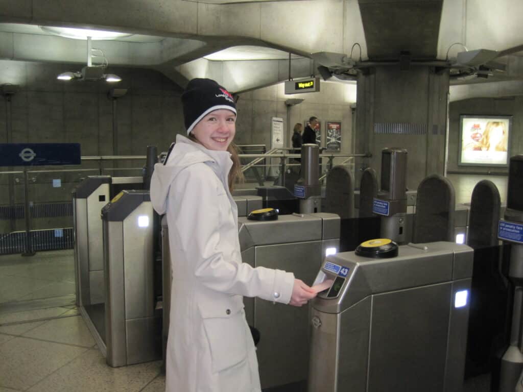 teen girl in beige coat and dark wool hat at Tube station in London
