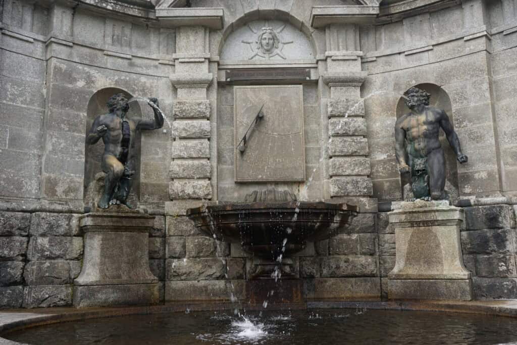 Powerscourt Garden - Sundial Fountain - stone structure with embedded sun dial flanked by two fountains from mouths of male figures.