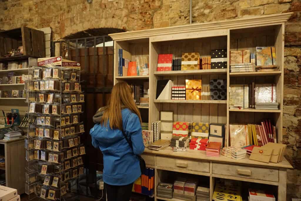 girl in bright blue coat looks at notebooks displayed in cabinet at Avoca in Powerscourt House.