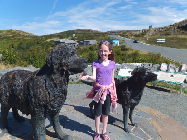 Young girl with Newfoundland and Labrador dog statues outside Johnson GEO Centre in St. John's, Newfoundland.