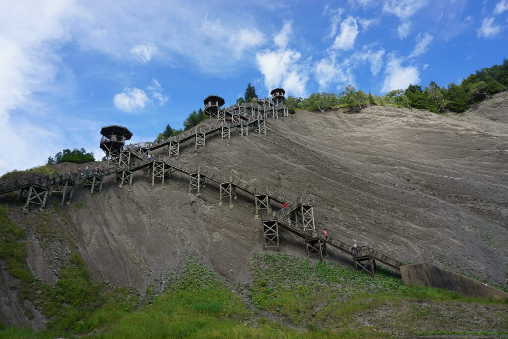 wooden staircase on side of cliff at Montmorency Falls with bright blue sky and wispy white clouds.