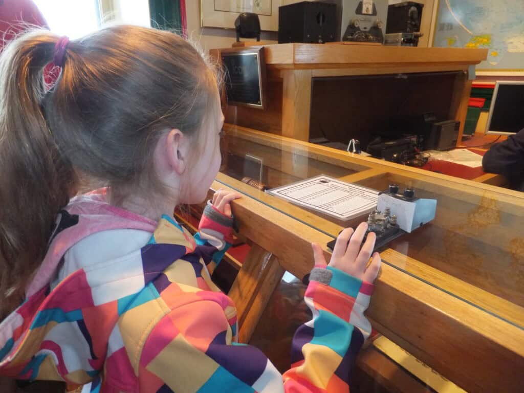 young girll with ponytail wearing multicoloured coat looking at displays in Cabot Tower on Signal Hill, St. John's, Newfoundland, Canada.