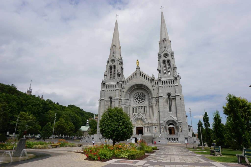 Exterior of the Basilica of Sainte-Anne-de-Beaupre-Quebec with flower gardens and small fountain in foreground.