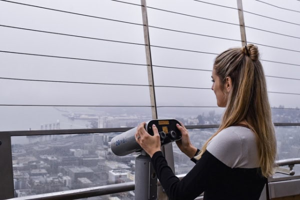 woman standing with telescope at Space Needle enjoying view of Seattle