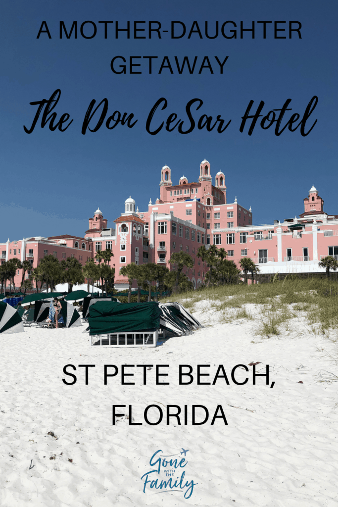 pink hotel on white sand beach with green beach chairs