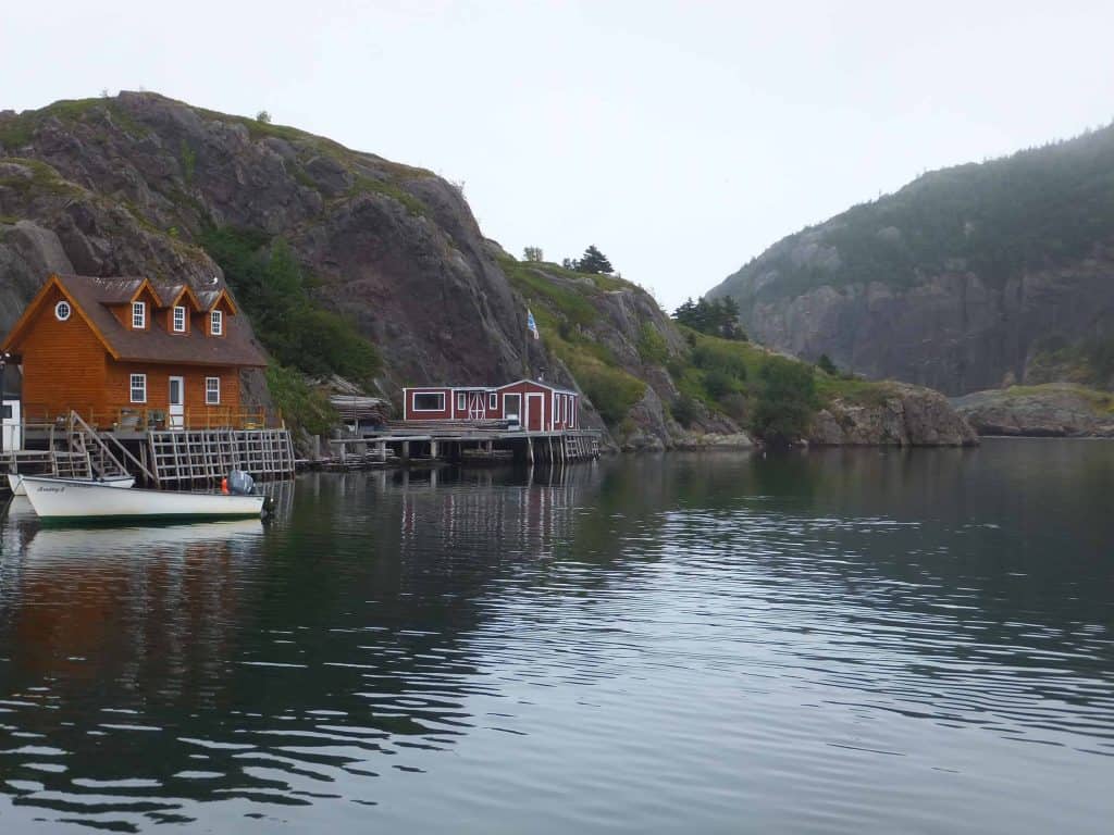 boat and buildings beside water with rocky hills behind in Quidi Vidi Village, St. John's, Newfoundland.