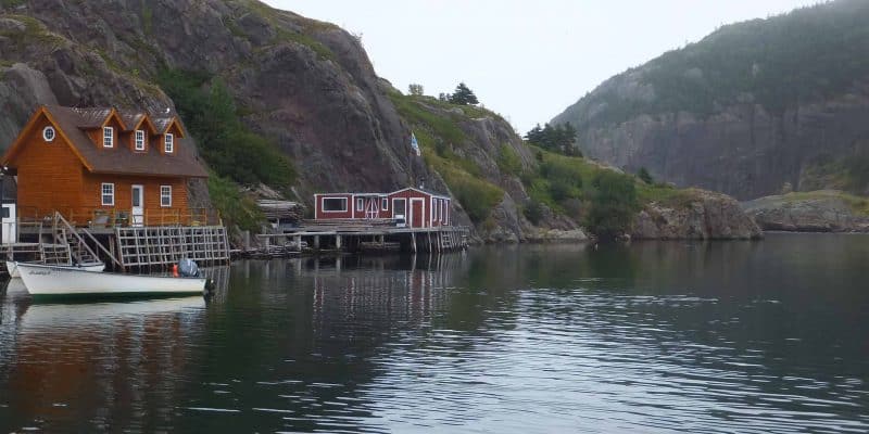 boat and buildings beside water with rocky hills behind