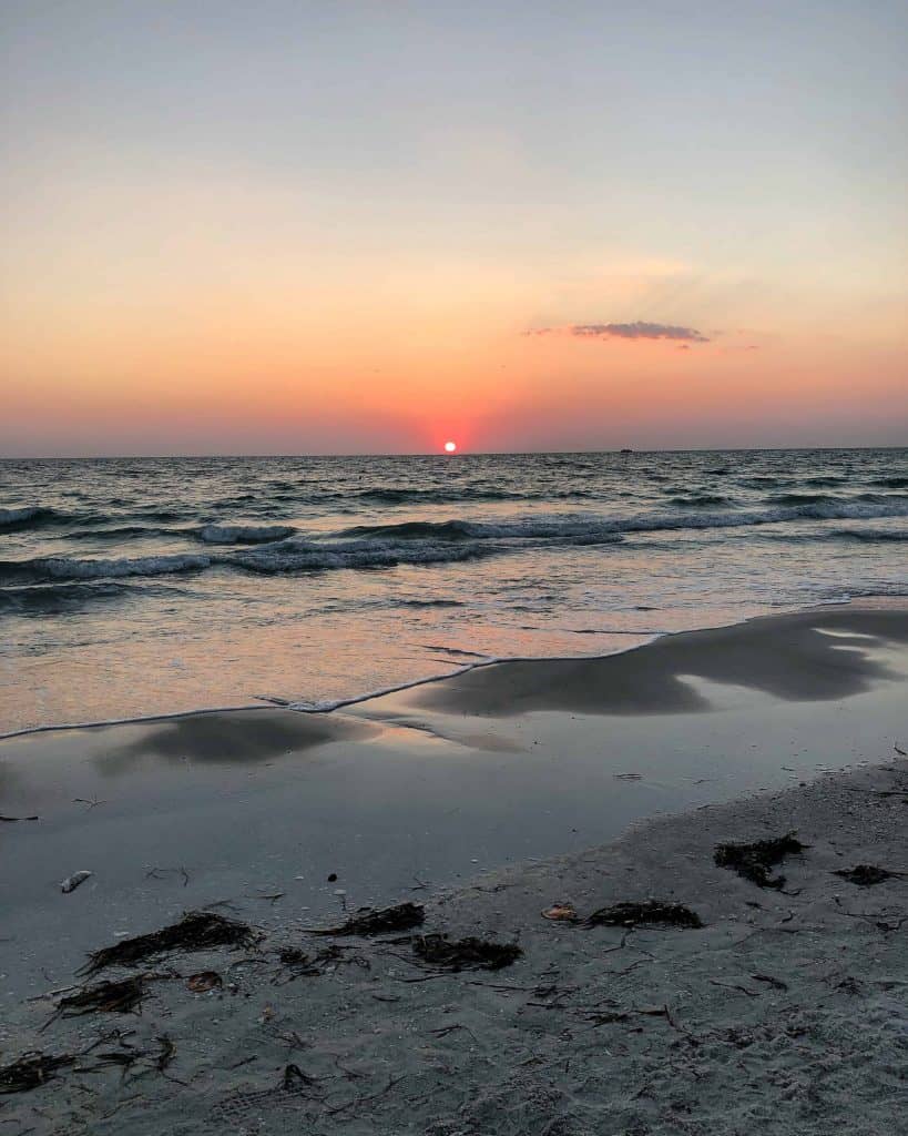 sun at horizon level setting over ocean at beach