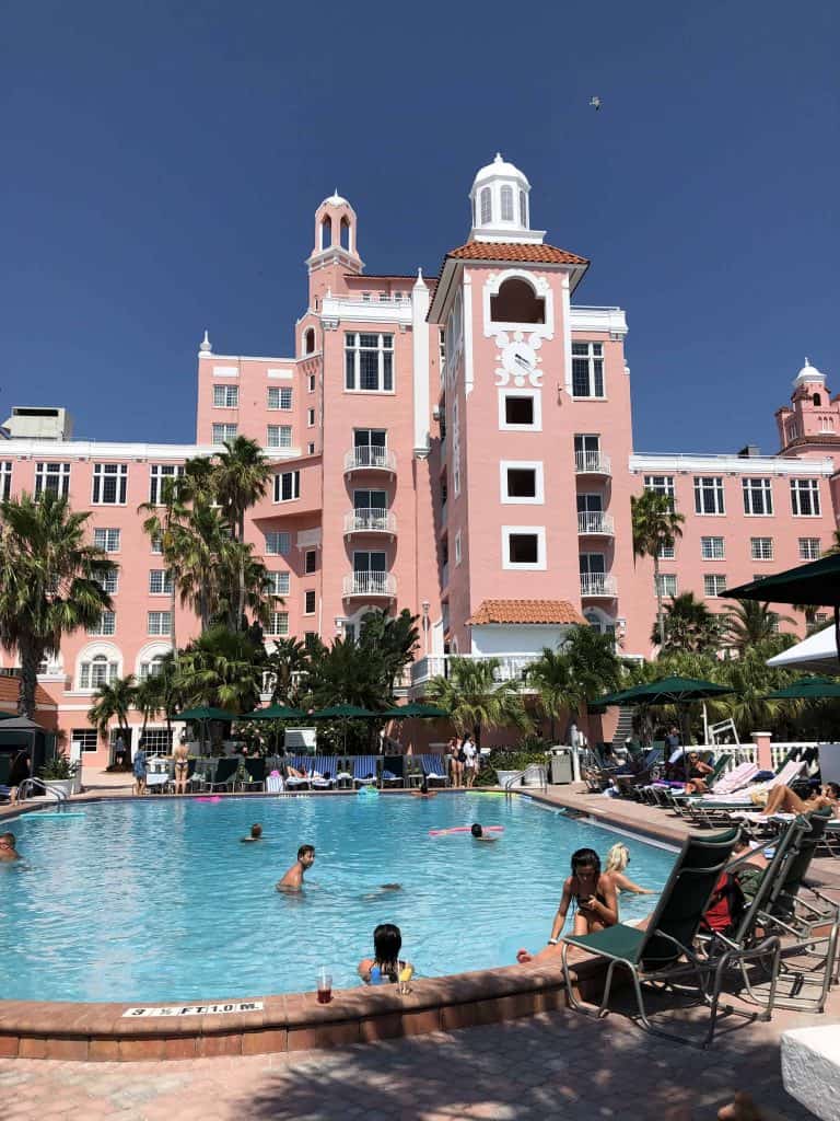 outdoor swimming pool with pink hotel in background