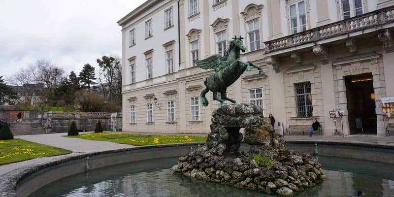 sculpture of winged horse in fountain beside white building