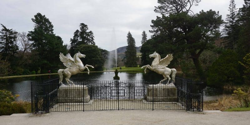 wrought iron gate winged horses in front of pond with fountain