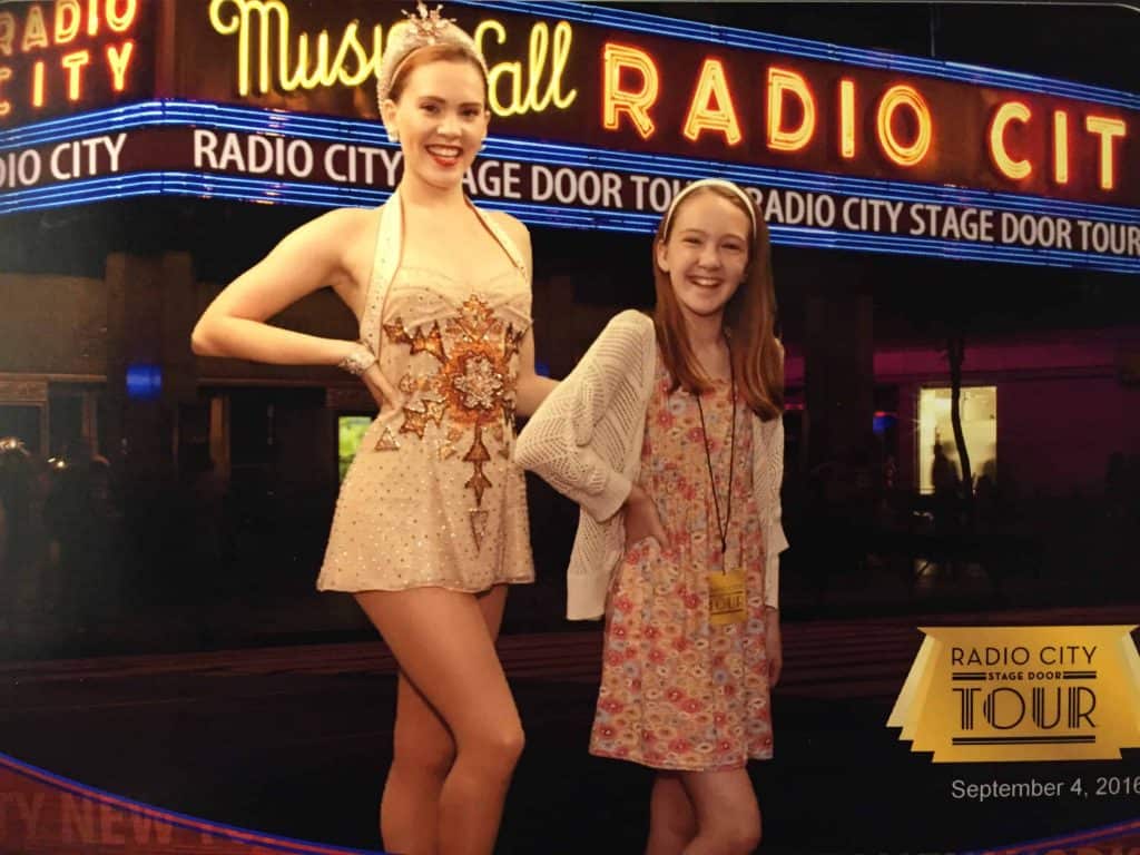 Teen girl posing with radio city rockette on tour of Radio City Music Hall.