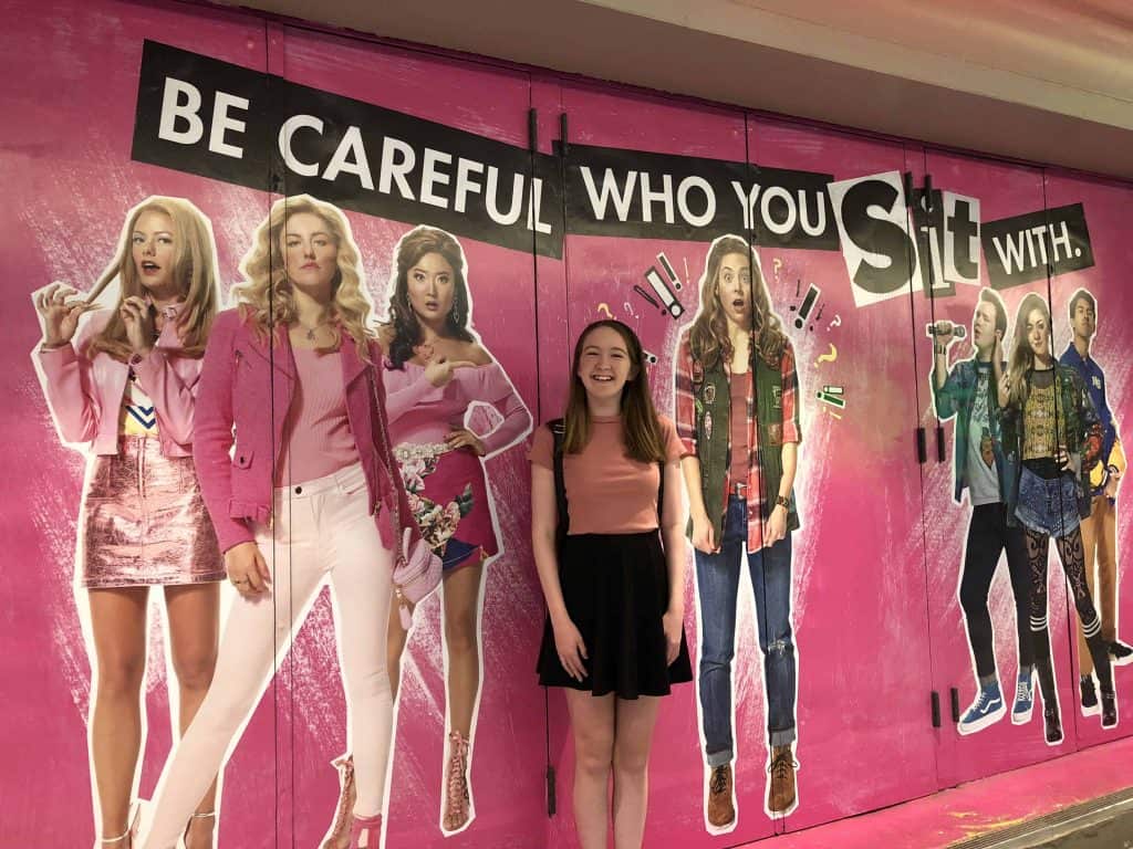 teen in front of mean girls poster