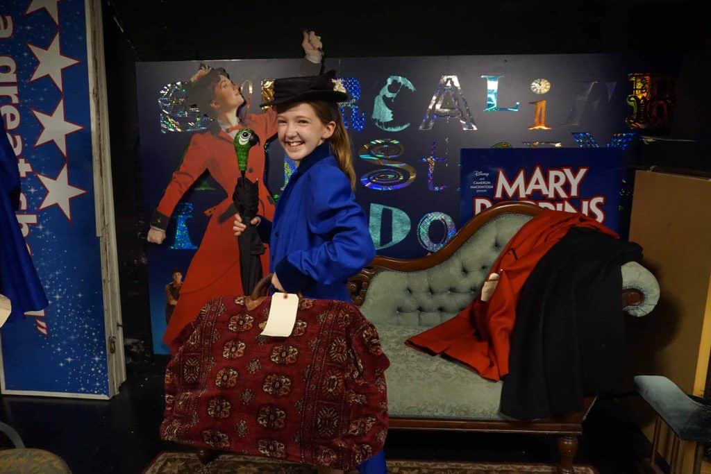 Teen girl dressed as mary poppins with props from broadway musical.