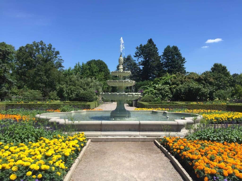 three level fountain in gardens with yellow and orange flowers