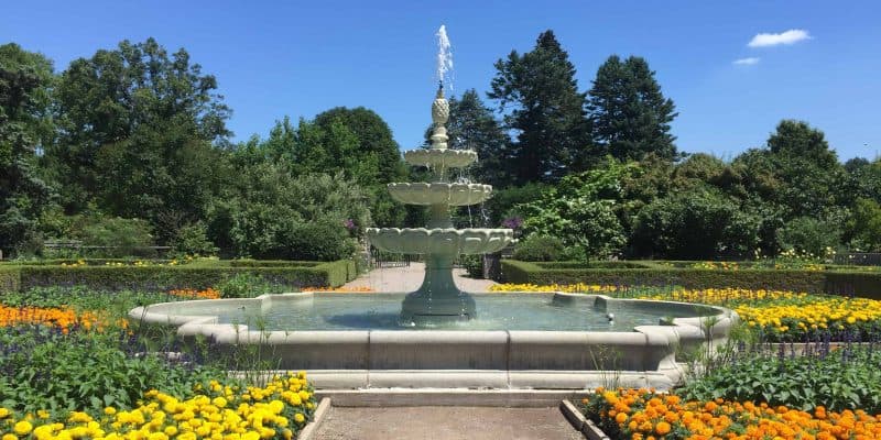 three level fountain in gardens with yellow and orange flowers