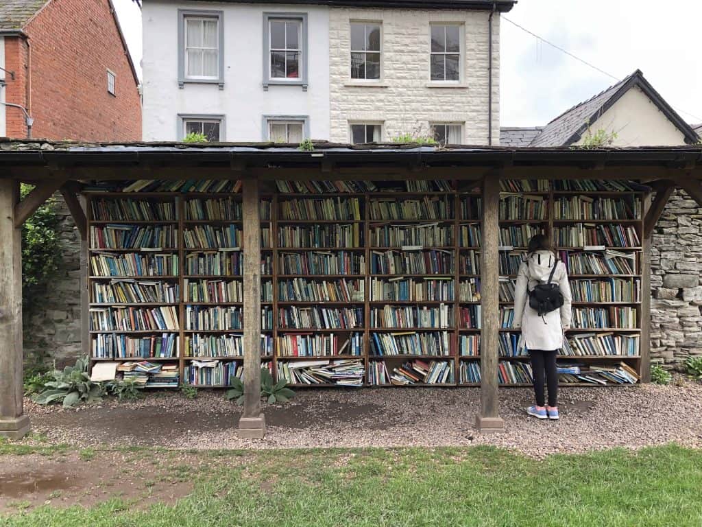 girl in front of open air book shelves in welsh village