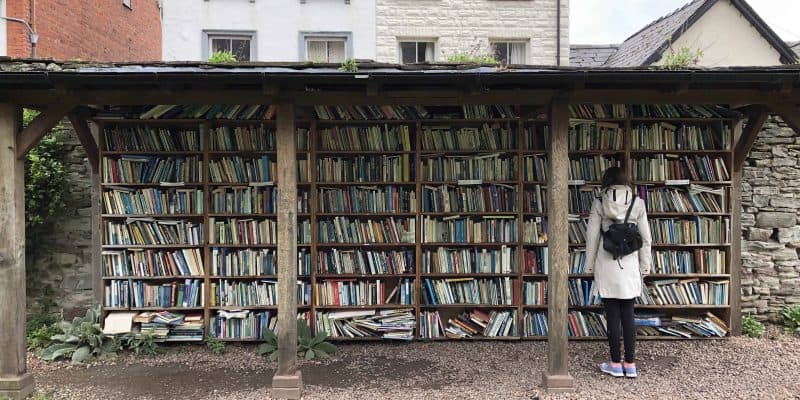 girl in front of open air book shelves in welsh village