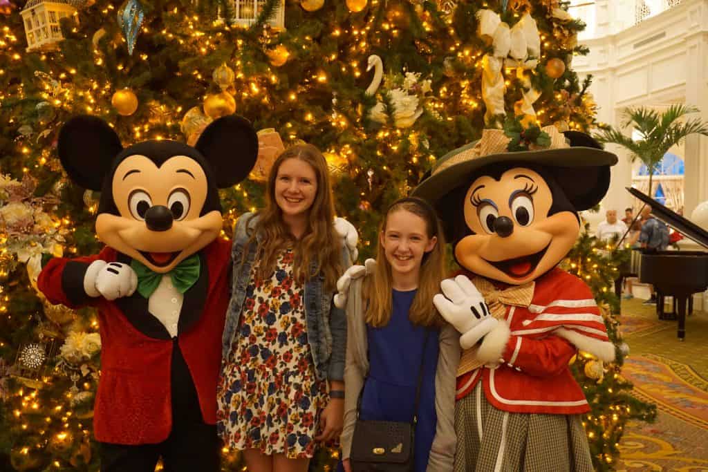 girls with Mickey and Minnie Mouse dressed in Victorian clothes in front of christmas tree