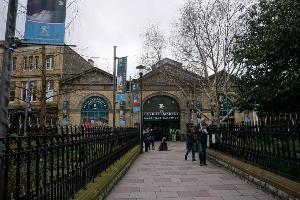 people walking in front of cardiff market building