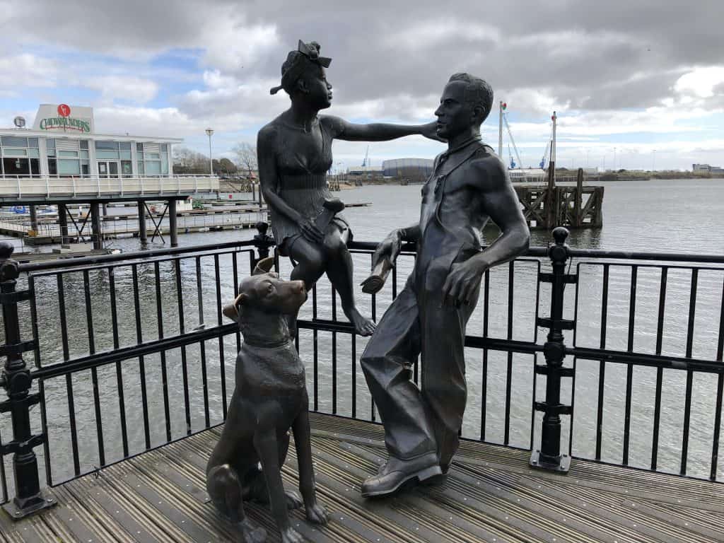 sculpture of man woman and dog on pier