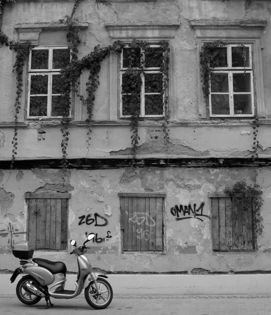 zagreb-lone scooter in front of building with grafitti in black and white