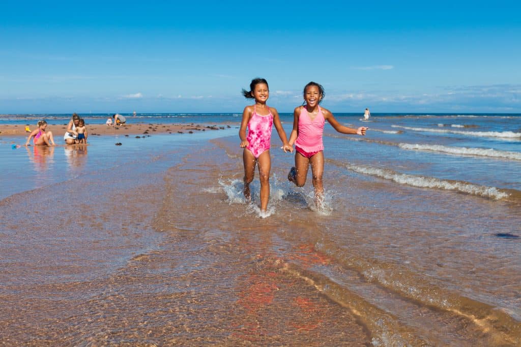 Two young girls in pink bathing suits playing on beach