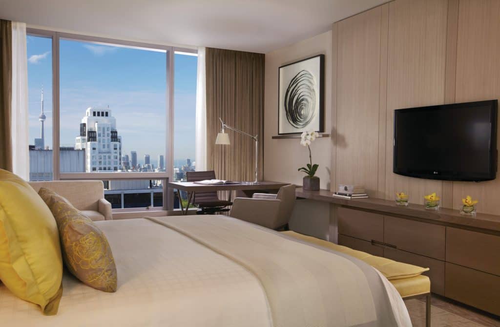 Four seasons hotel toronto guest room with bed, television and window with view of city.