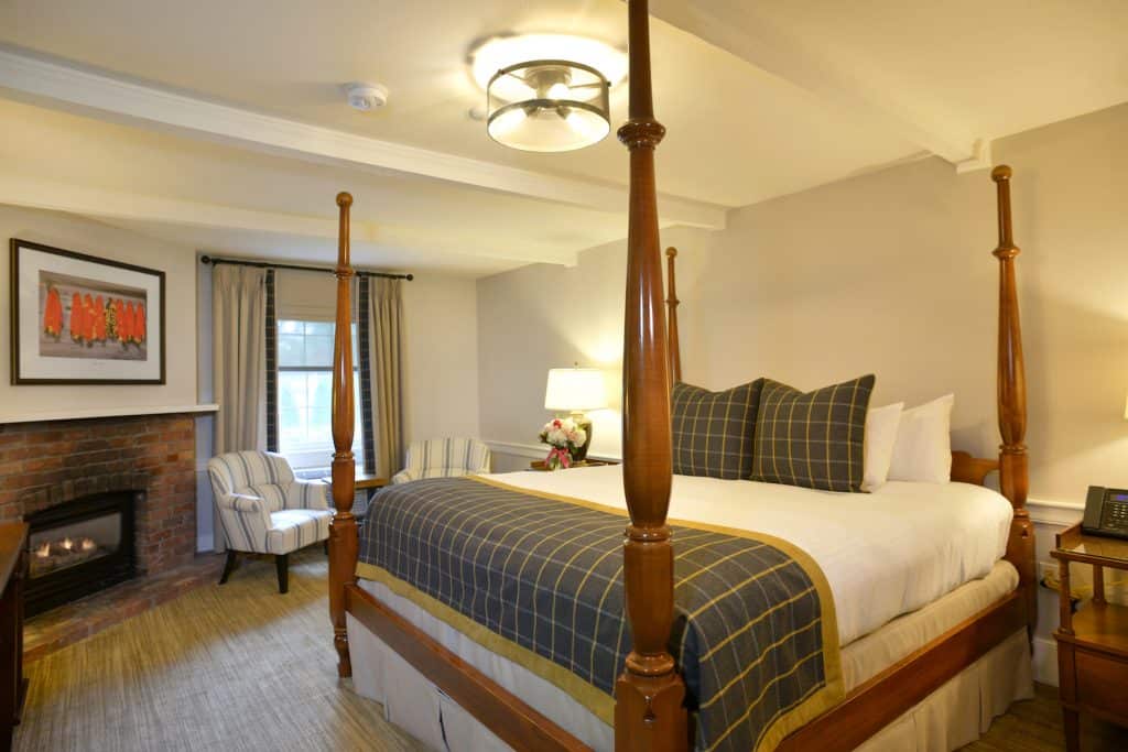 Pillar & Post Hotel in Niagara-on-the-Lake, Ontario - Guest Room with four poster bed, brick fireplace and seating area.