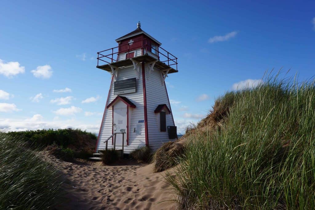 red and white lighthouse on sand dune at covehead-prince edward island