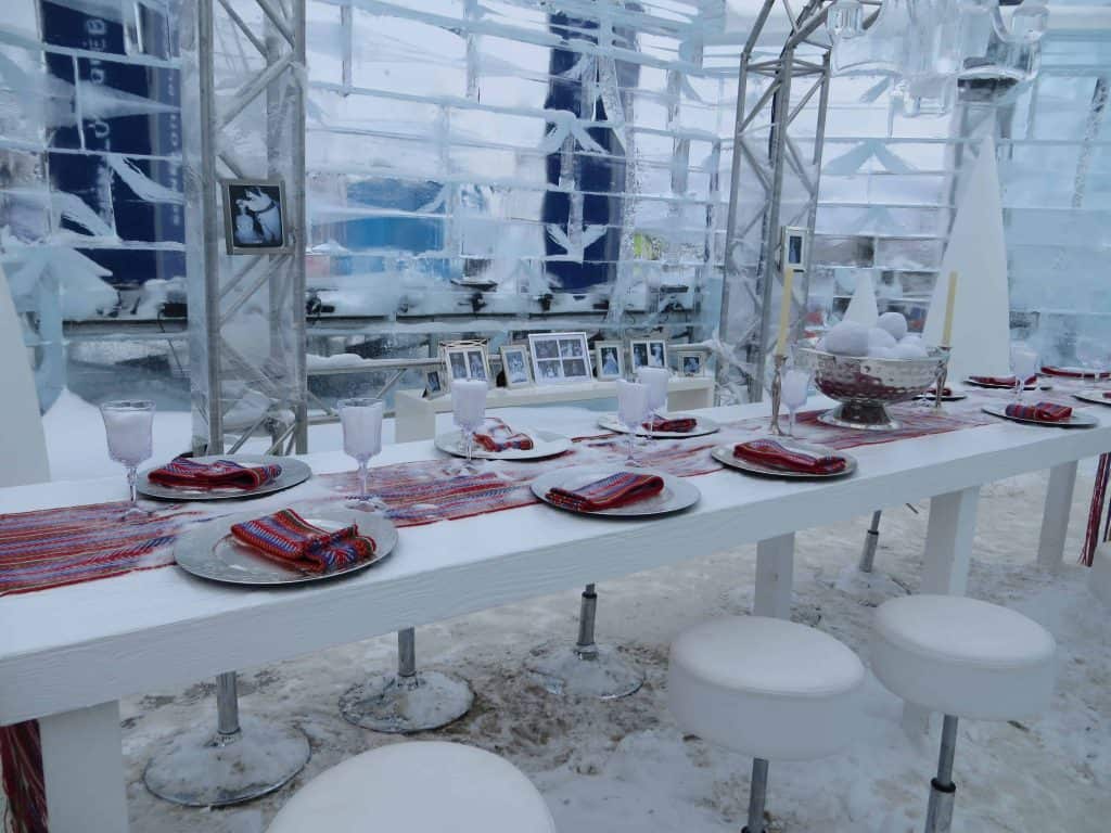 Dining table set with plates, glasses and red arrow sashes inside Bonhomme's palace at the quebec winter carnival in Quebec City.