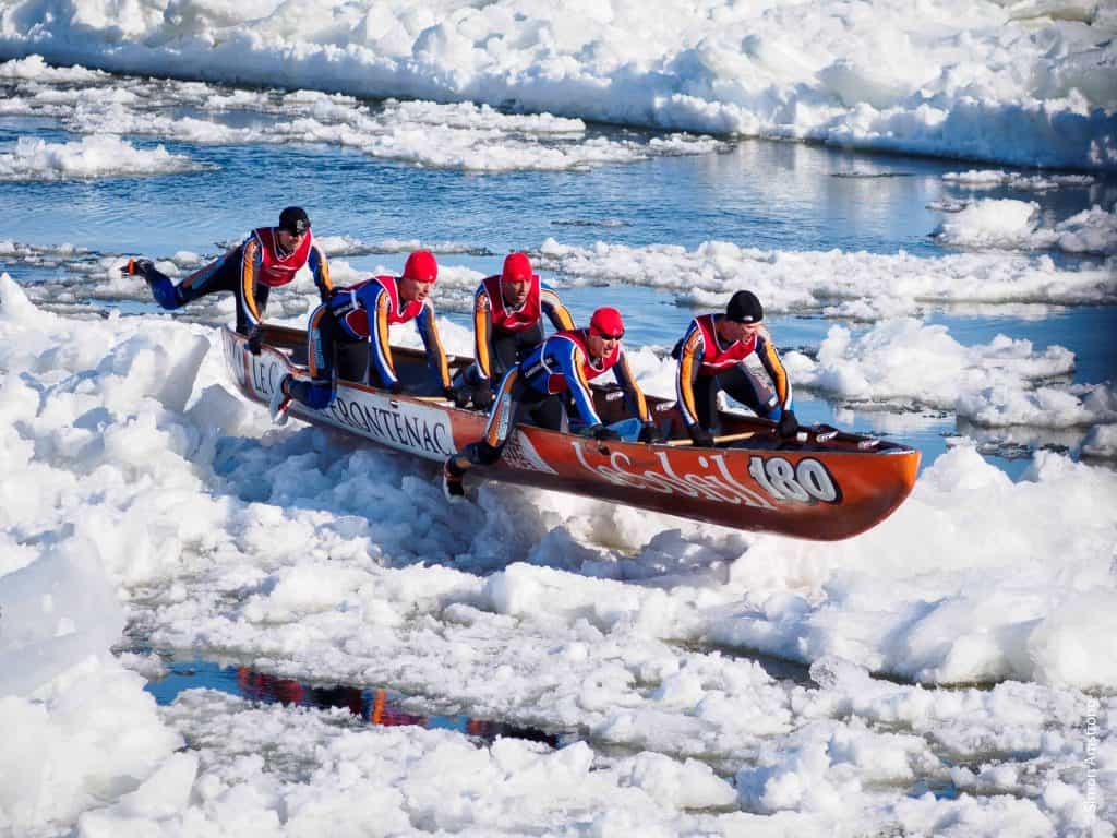 five men in a canoe on ice and water in St. Lawrence River in quebec city during the carnival's ice canoe race.