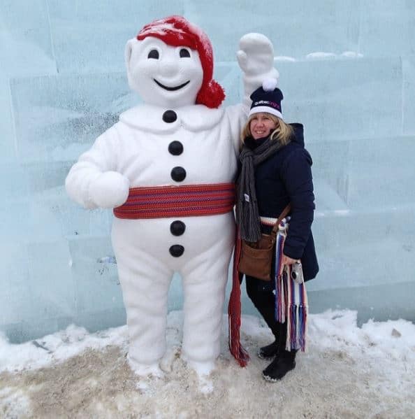 Woman with Bonhomme inside ice palace at quebec winter carnival.