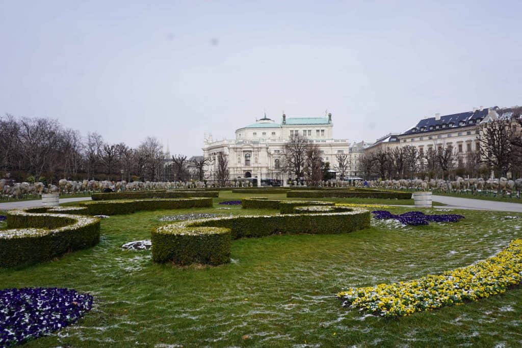 buildings and garden in vienna with flowers and light snow