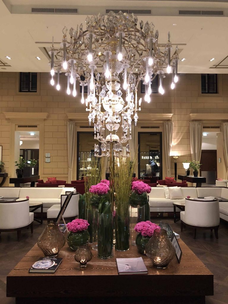 kempinski hotel vienna lobby-crystal chandelier-table vases pink flowers