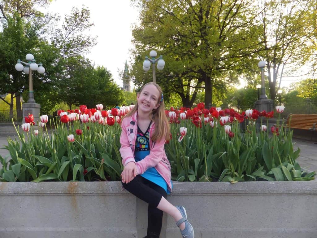 Young girl sitting in front of bed of tulips in Major's Hill Park in Ottawa, Canada. 