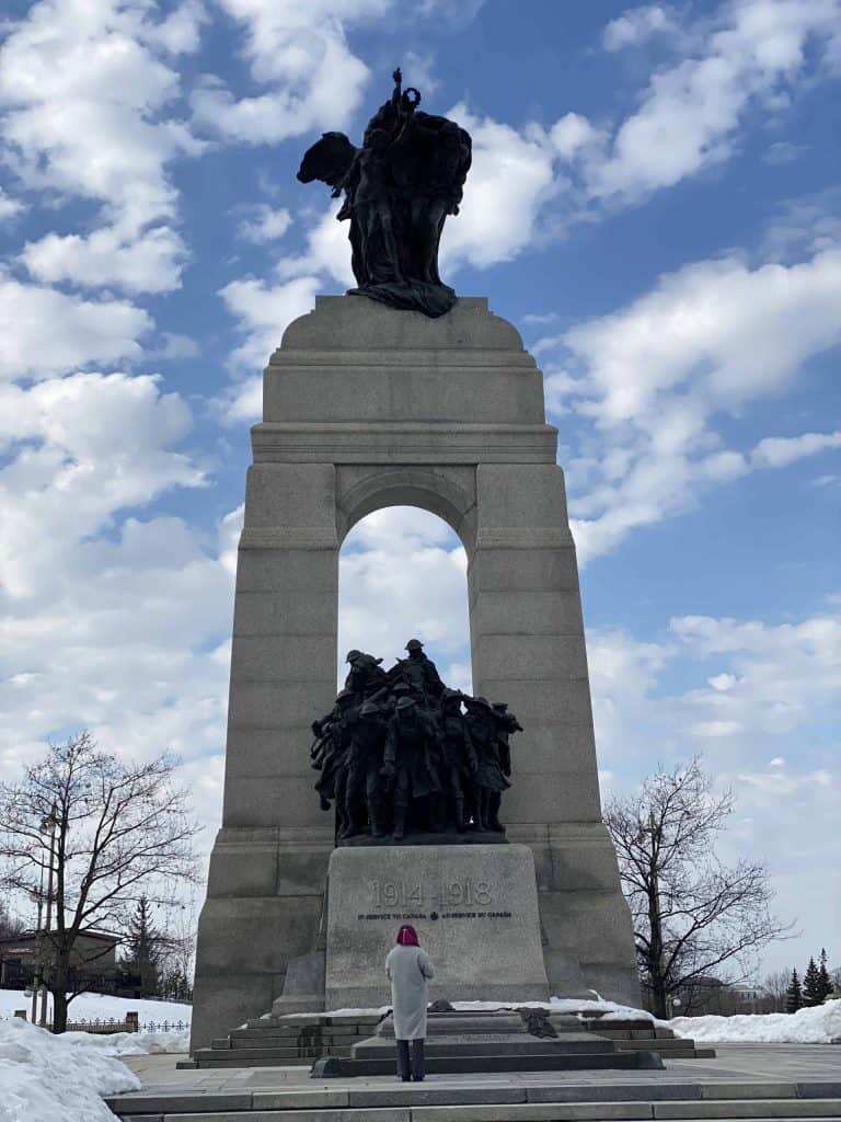 Woman standing in front of National War Memorial in Ottawa in winter with snow on ground.