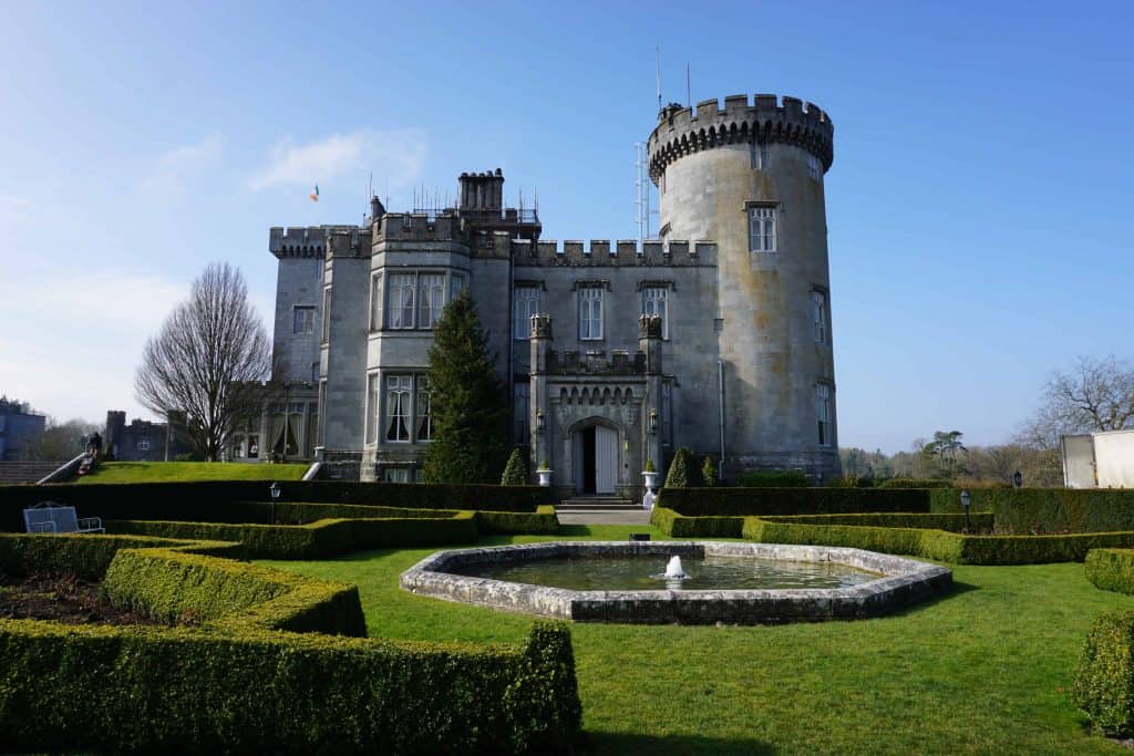 Exterior of Dromoland Castle in County Clare, Ireland with garden hedges and small stone fountain.