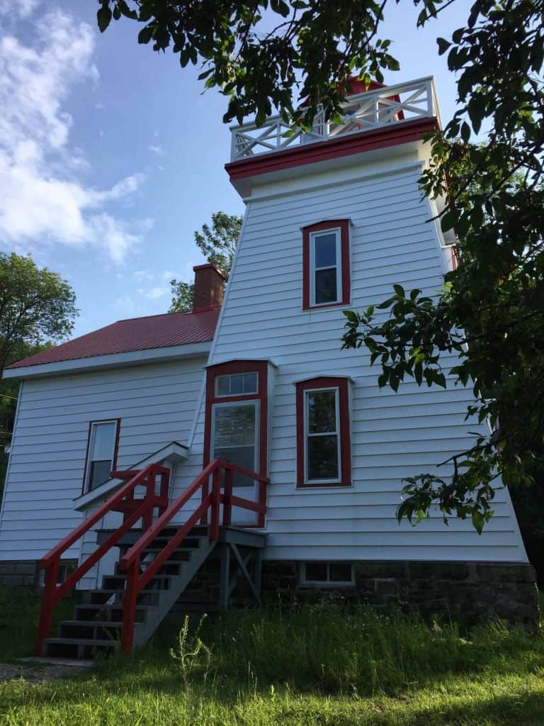 janet head lighthouse in Gore Bay on Manitoulin Island - white wooden clapboard lighthouse and keeper's quarers with red roof, window trip and staircase.